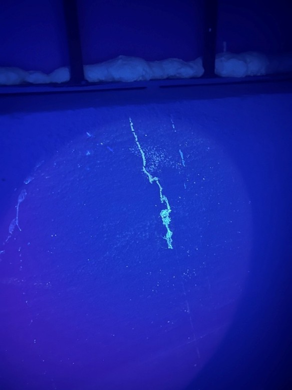Dieselbe Wand unter UV-Licht – Riss und Feuchteeinbruch fluoreszieren deutlich